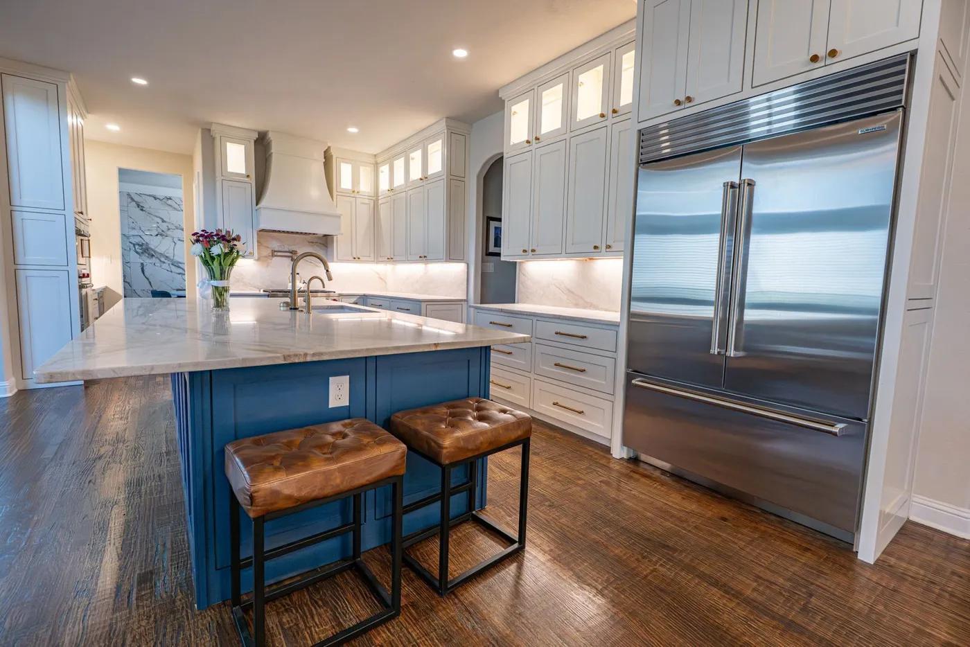 Illustrative large kitchen with a built-in stainless refrigerator beside a marble-topped island