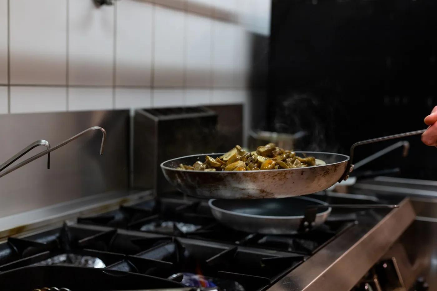 Food sautéing in a pan on a professional gas range