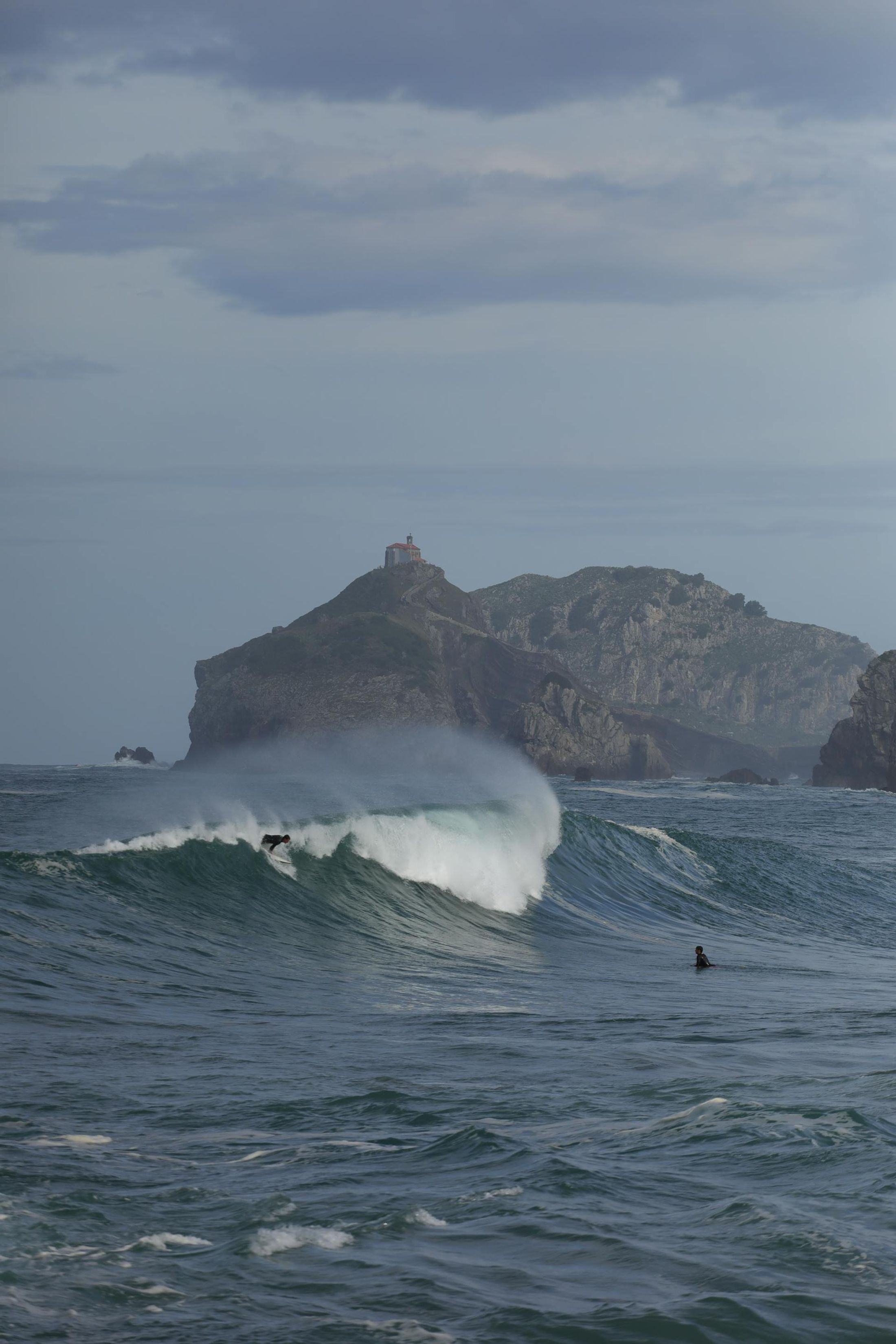 Surfeurs sur les vagues près de Gaztelugatxe, Pays Basque