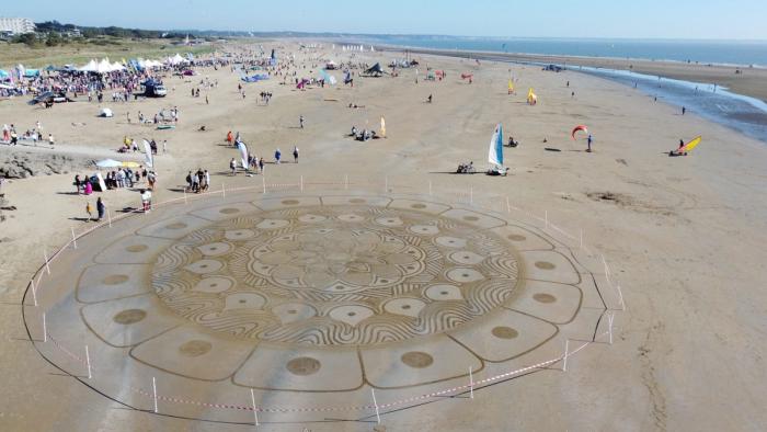 Vue aérienne du Week-end Glisse Saint-Brévin : mandala de sable au premier plan, village des exposants, kites et chars à voile sur la plage de l'Océan. Crédit : Saint-Brévin Tourisme.