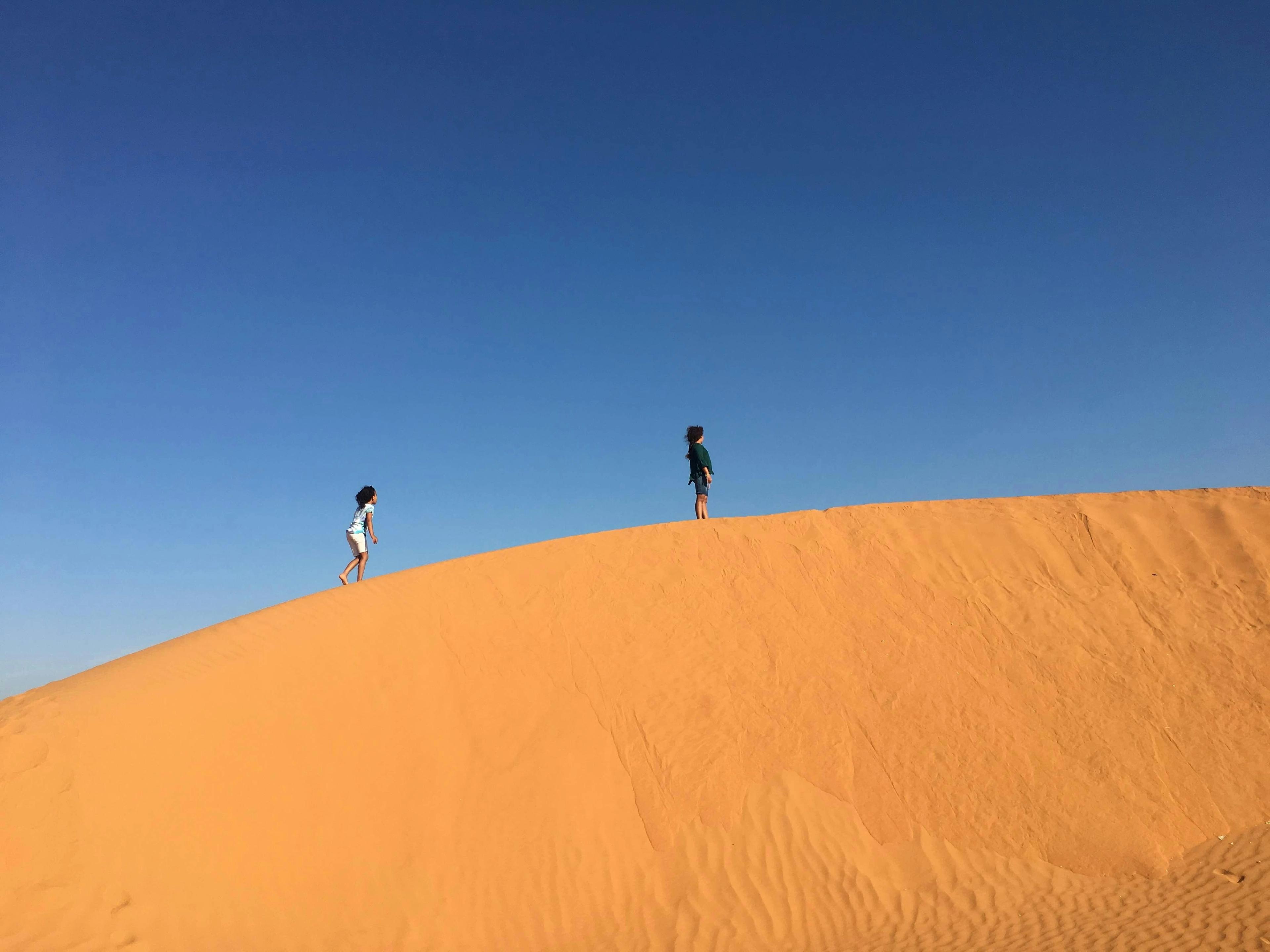 2 kids standing on sand dune