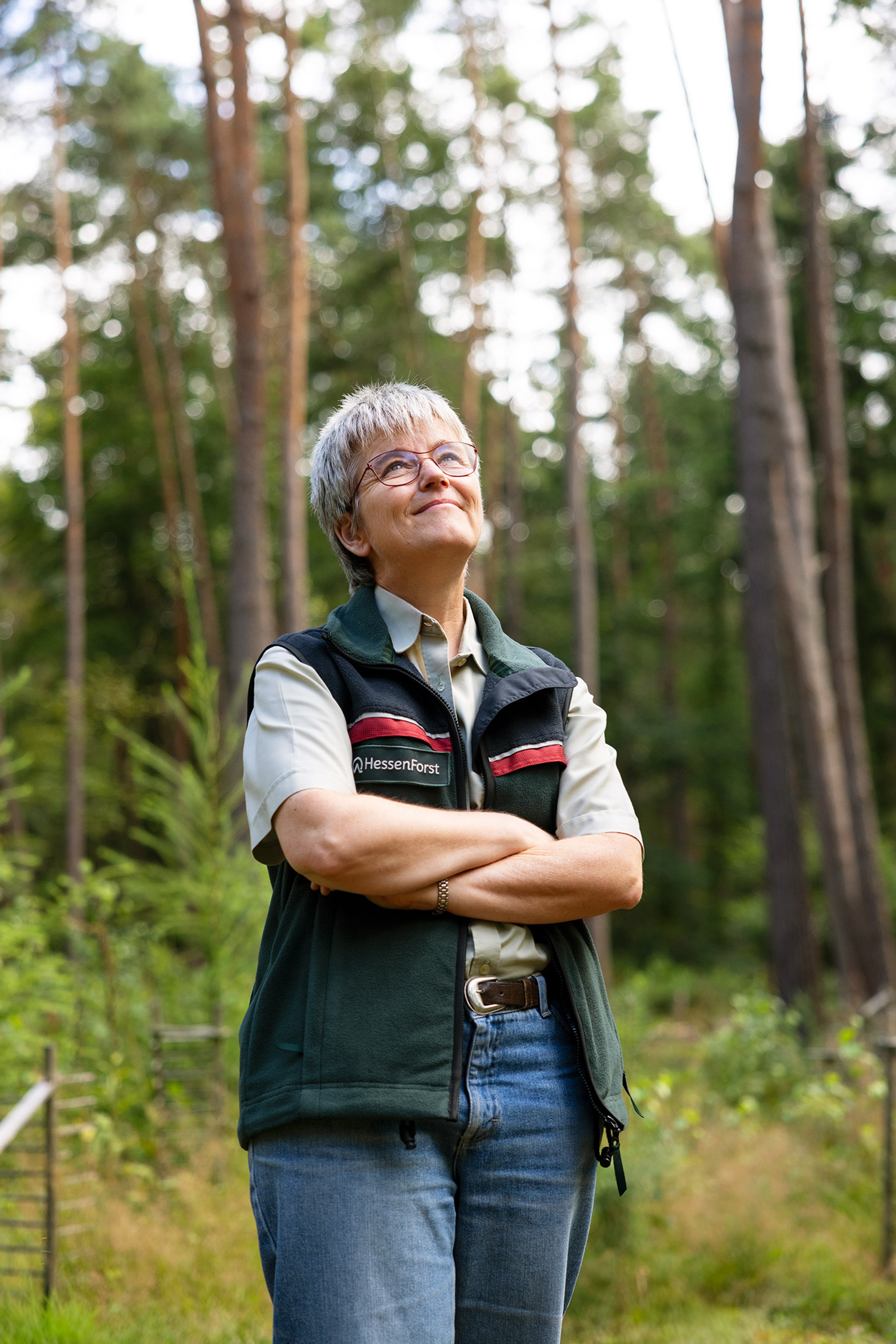 Frau im Wald guckt lächelnd nach oben