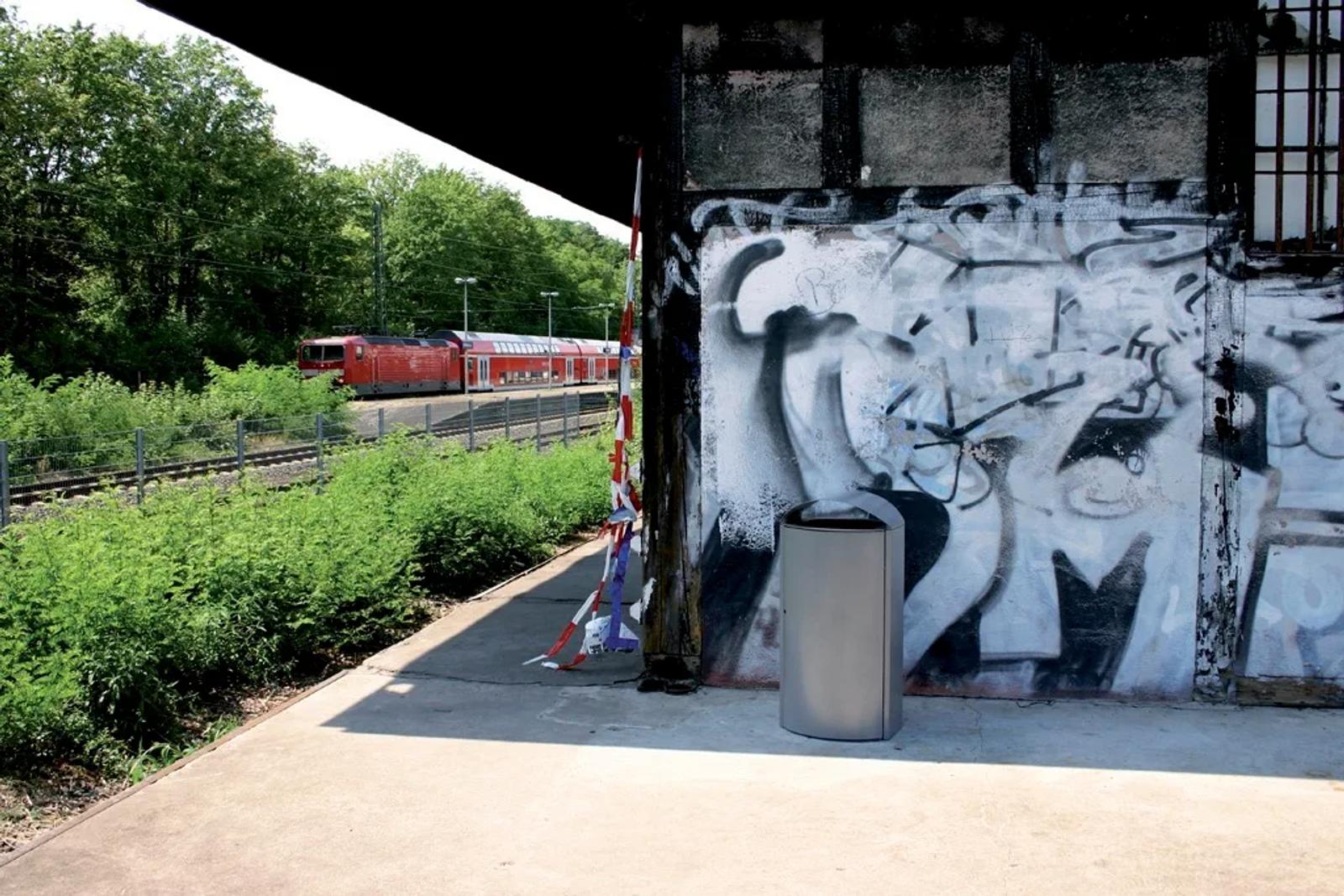 sauberer Kendo-Behälter vor einer Graffiti-Wand an einem bahnhof