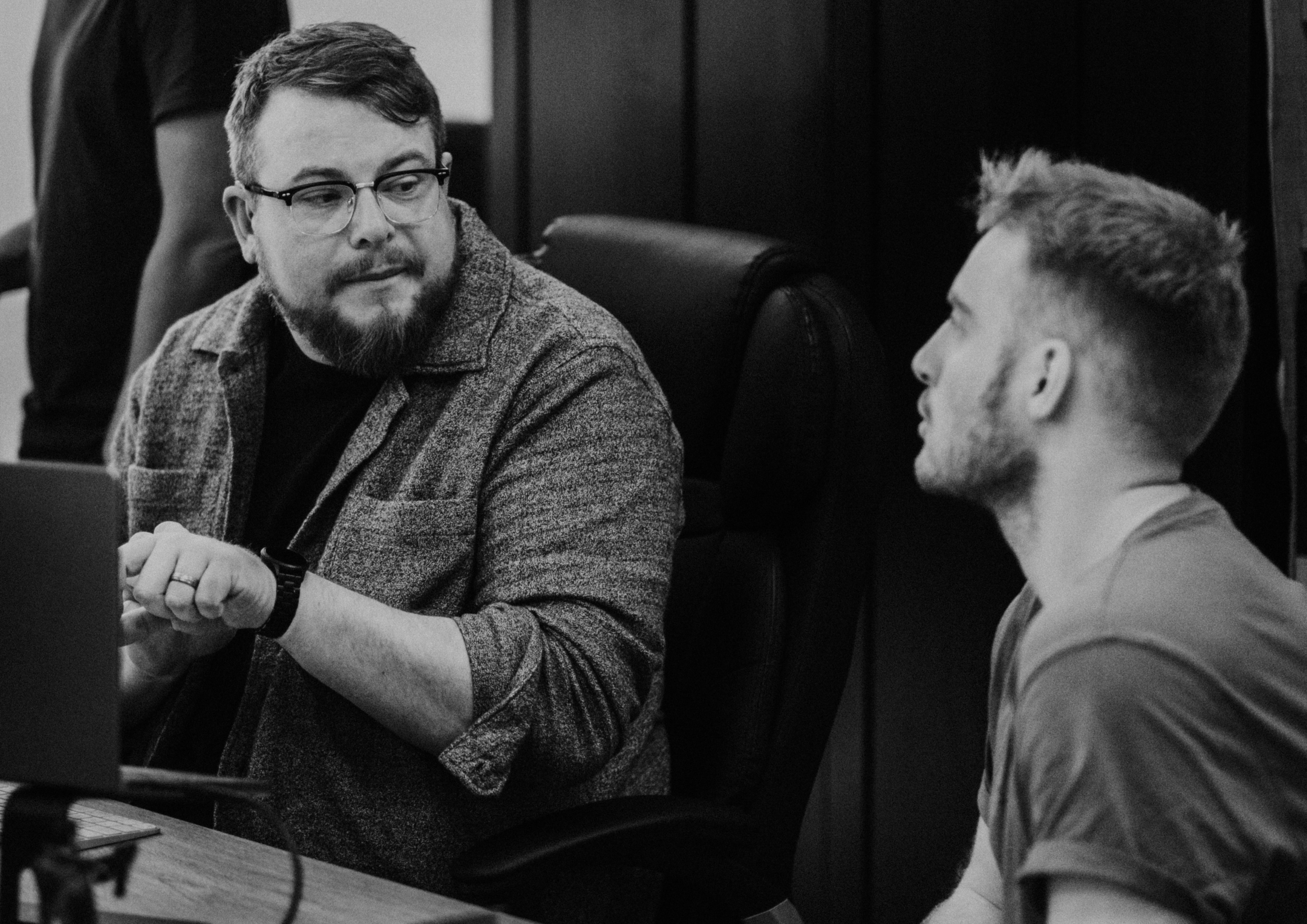 Scott Bennett in discussion with a colleague at his desk in the NOSY studio, MacBook open in front of him.