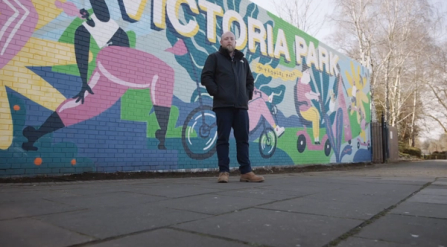 A man standing in front of Victoria Park mural in Portsmouth