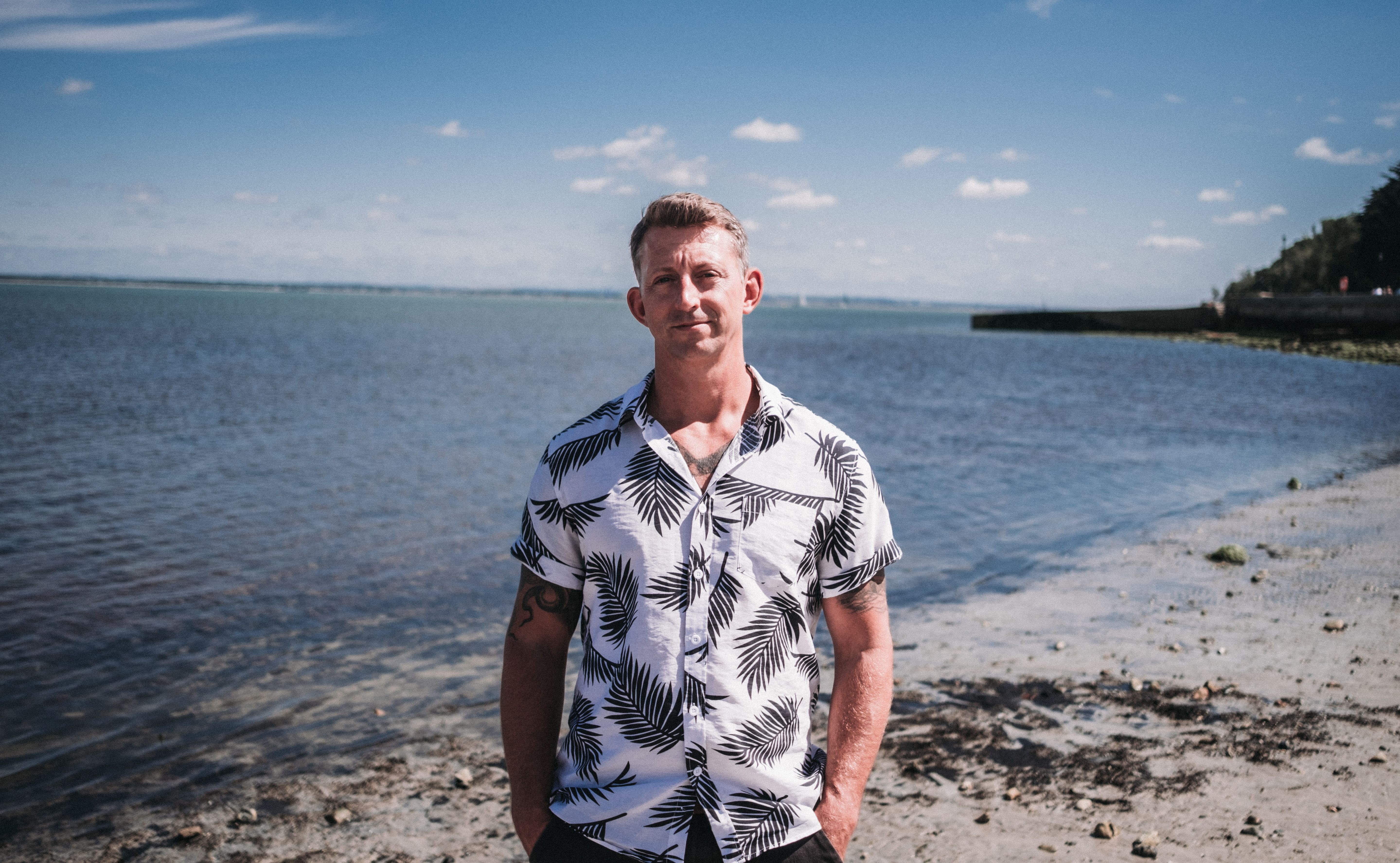 Professional headshot of Dan Carley, Client Director at NOSY Agency, wearing a white shirt with a seaside background.