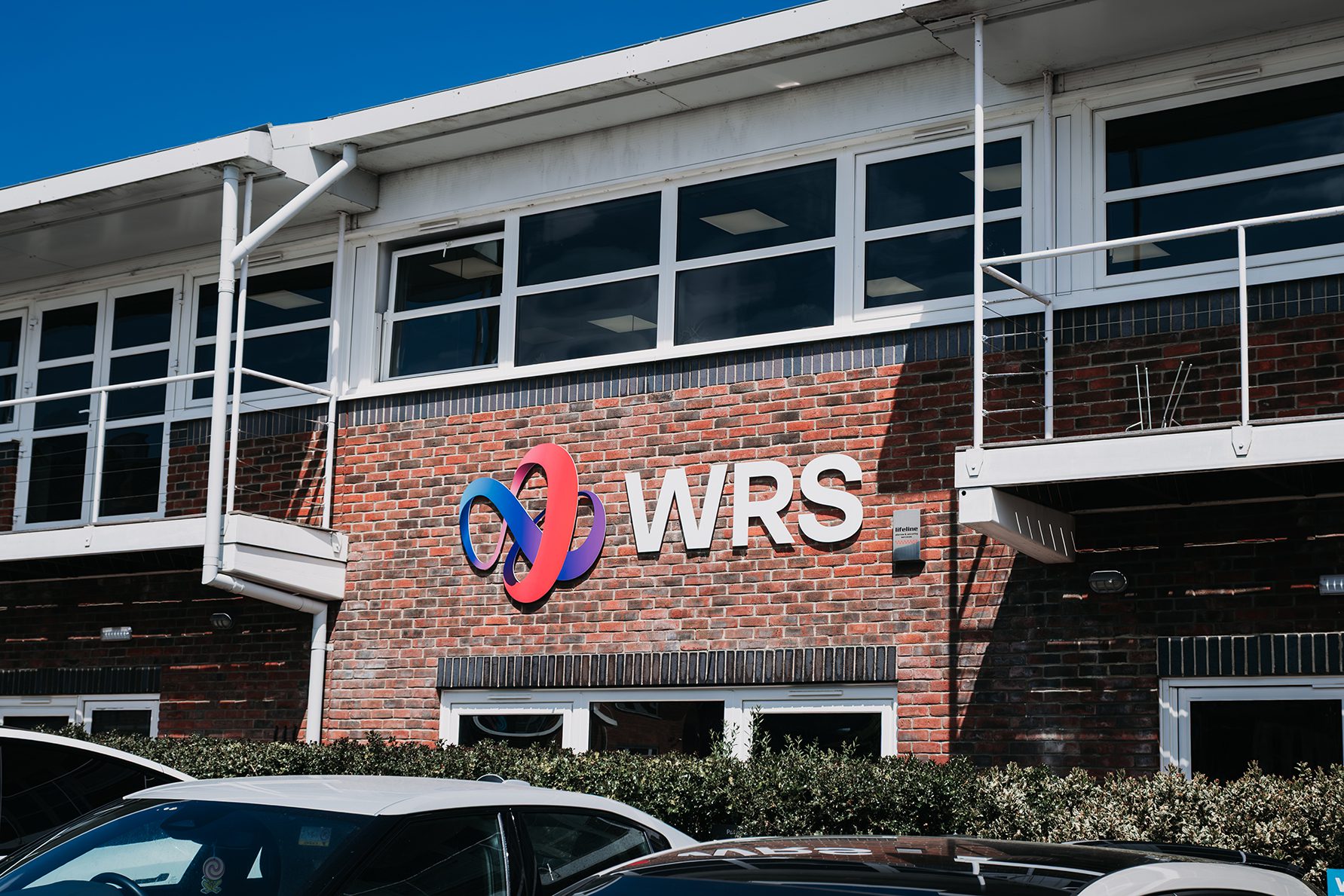 WRS logo on the front of a brick office building with interlinked red and blue gradient symbol.