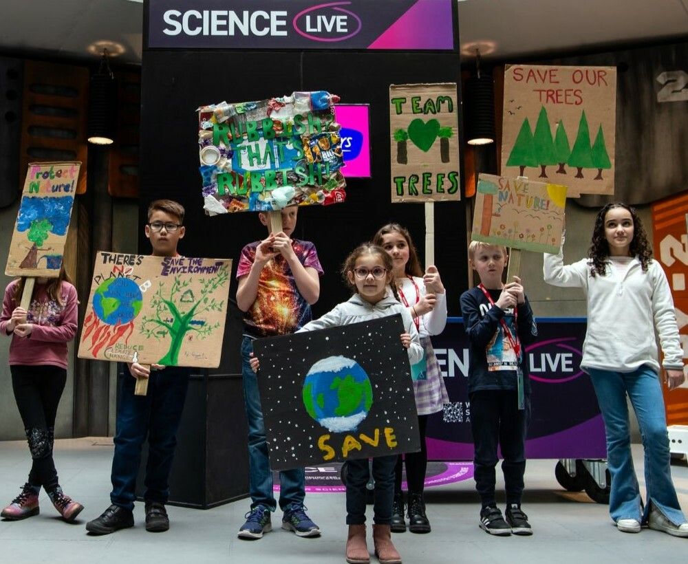 A group of children holding banners with "save our trees" messages