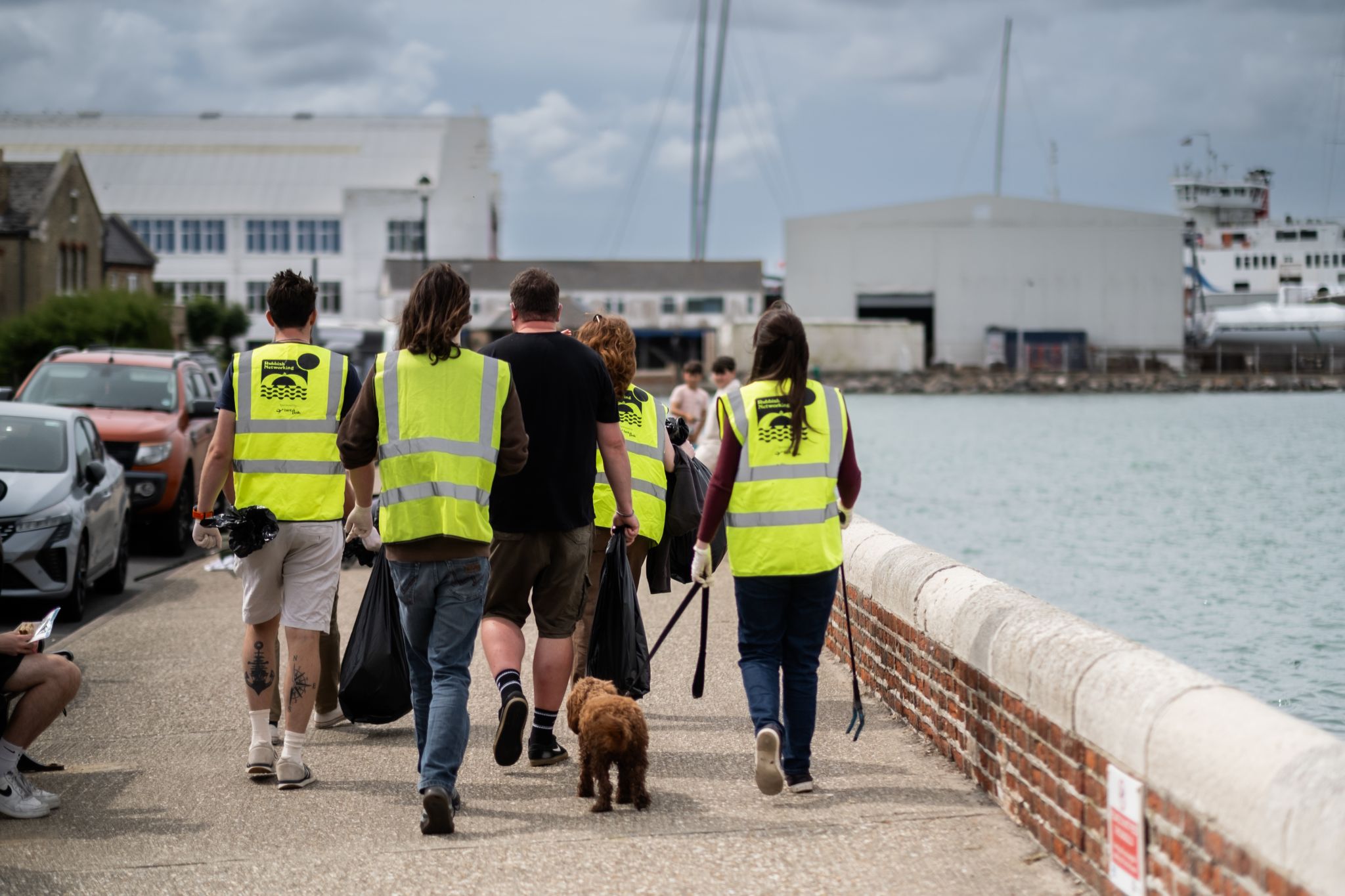 Volunteers in high-visibility vests collecting litter along East Cowes waterfront during NOSY’s Rubbish Networking clean-up event.