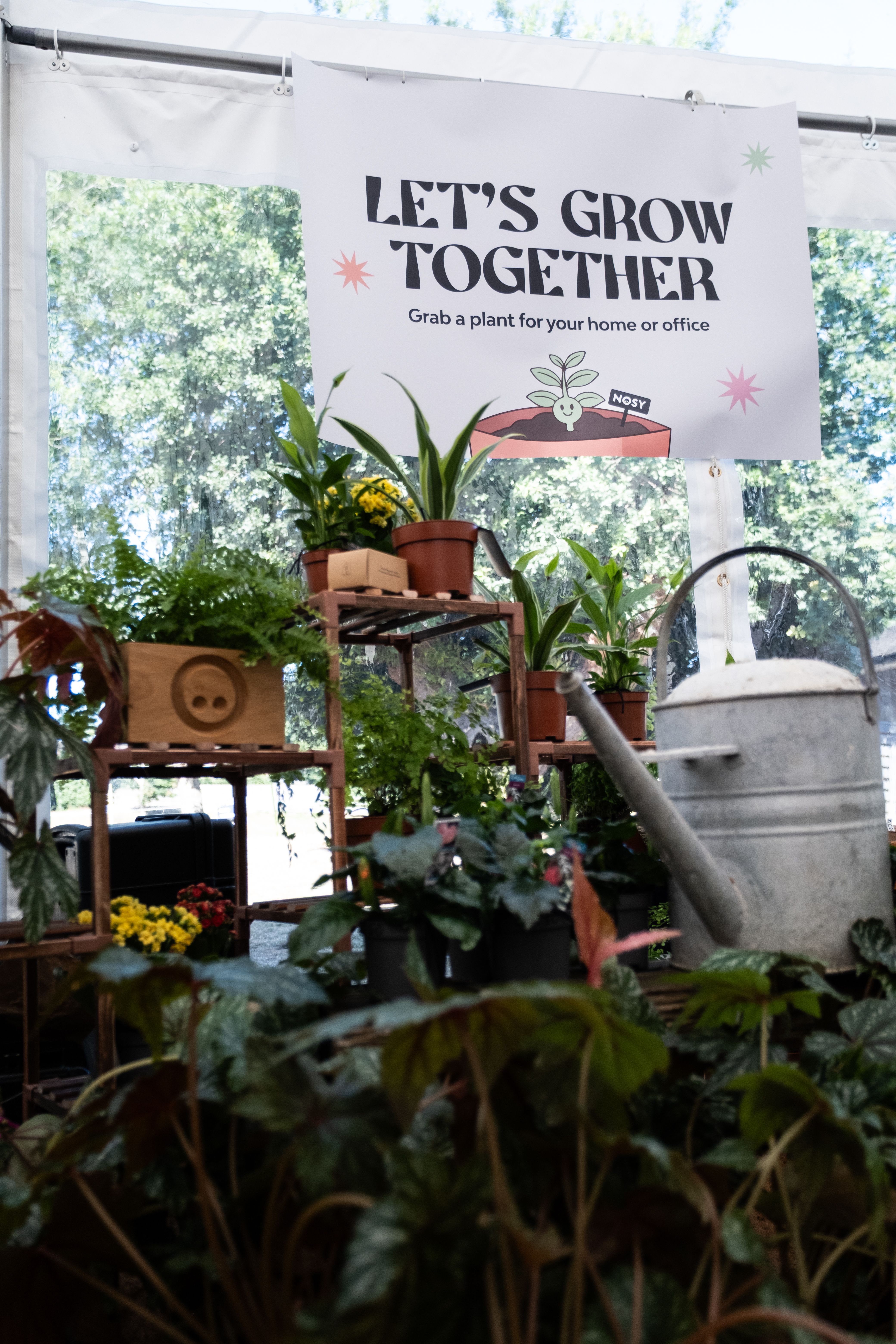 Close-up of NOSY’s vibrant plant display beneath the “Let’s Grow Together” sign