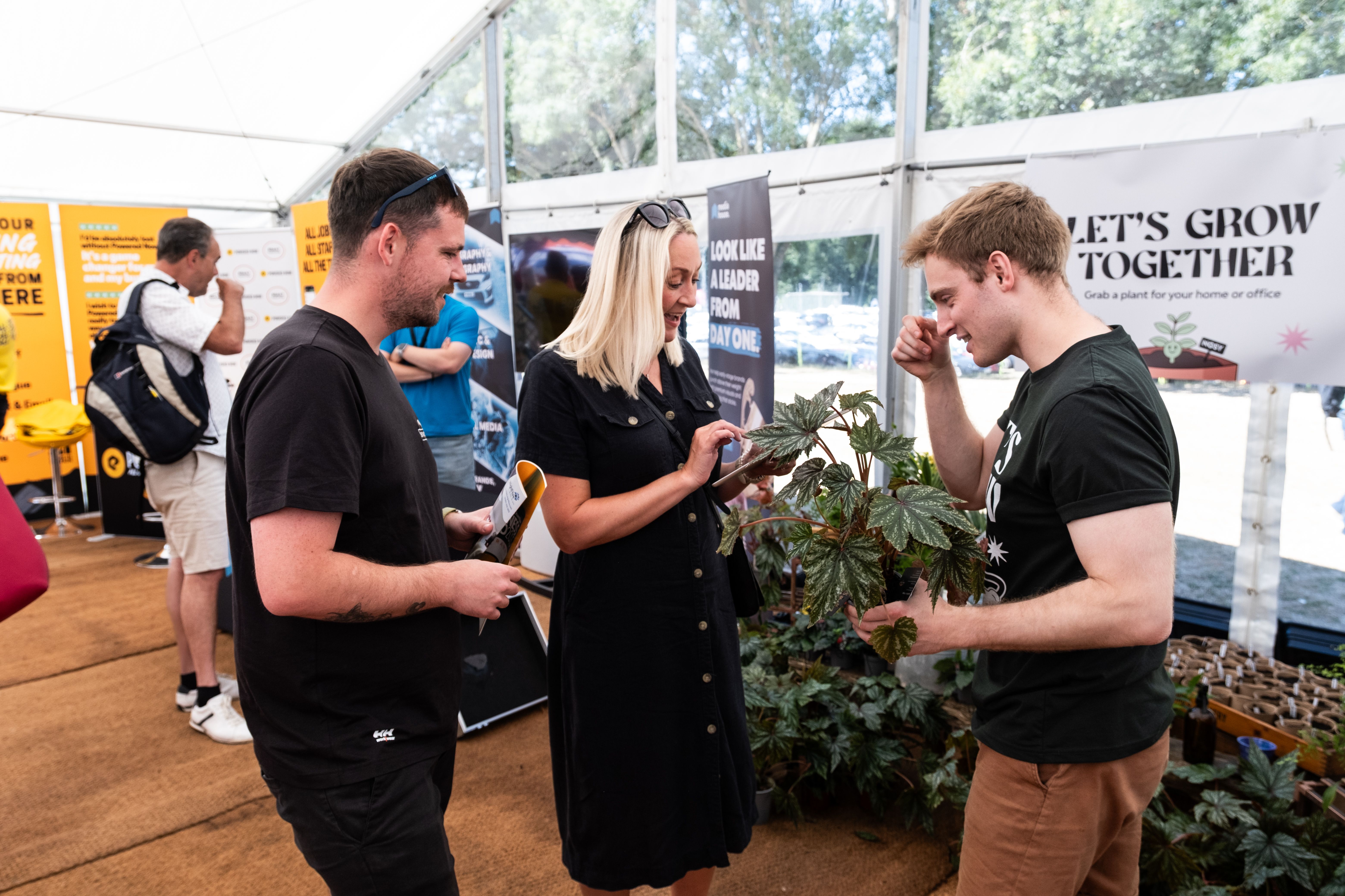 NOSY team member holding a plant while chatting with an attendee at the Chamber Expo