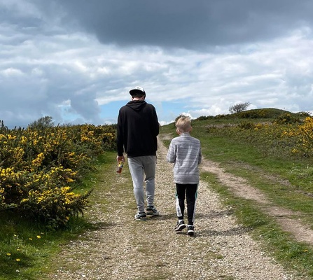 'Walk for Wildlife' over a background of an individual walking through the woods. Featuring the Hampshire & Isle of Wight Wildlife Trust logo