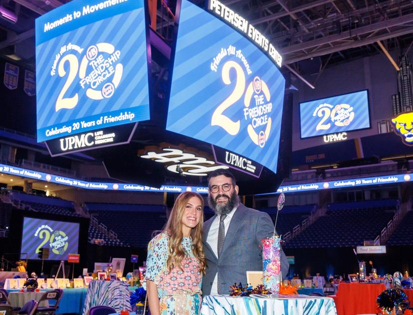 Friends All Around logo is on the Jumbotron at the Petersen Events Center, behind Rivkee and Rabbi Mordy Rudolph
