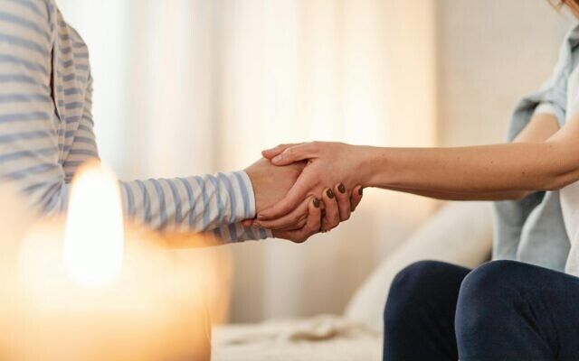 Two people holding hands during a supportive conversation, symbolizing comfort, empathy and emotional support