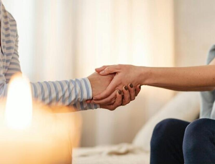 Two people holding hands during a supportive conversation, symbolizing comfort, empathy and emotional support