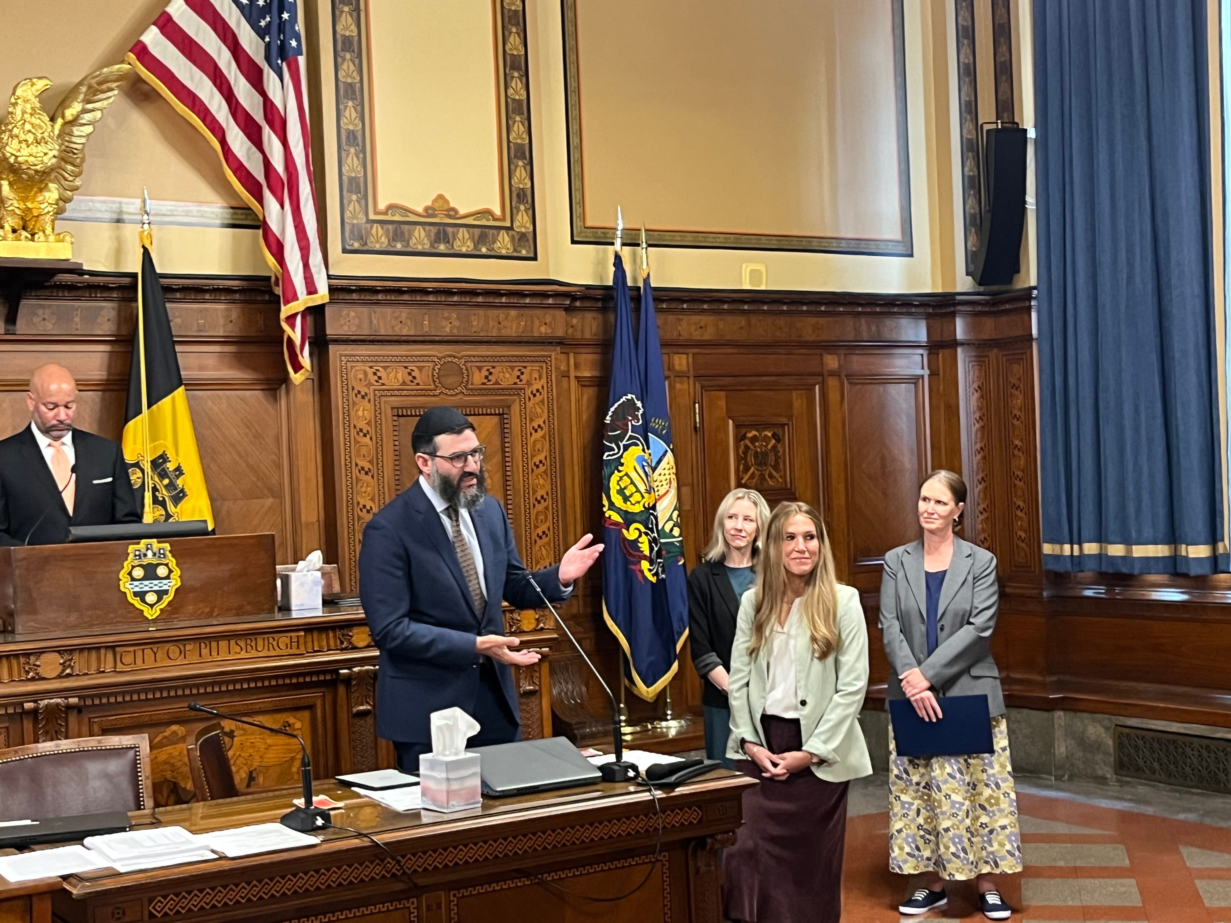 Rabbi Mordy Speaks at Podium in City Hall, Accepts Friendship Circle Proclamation