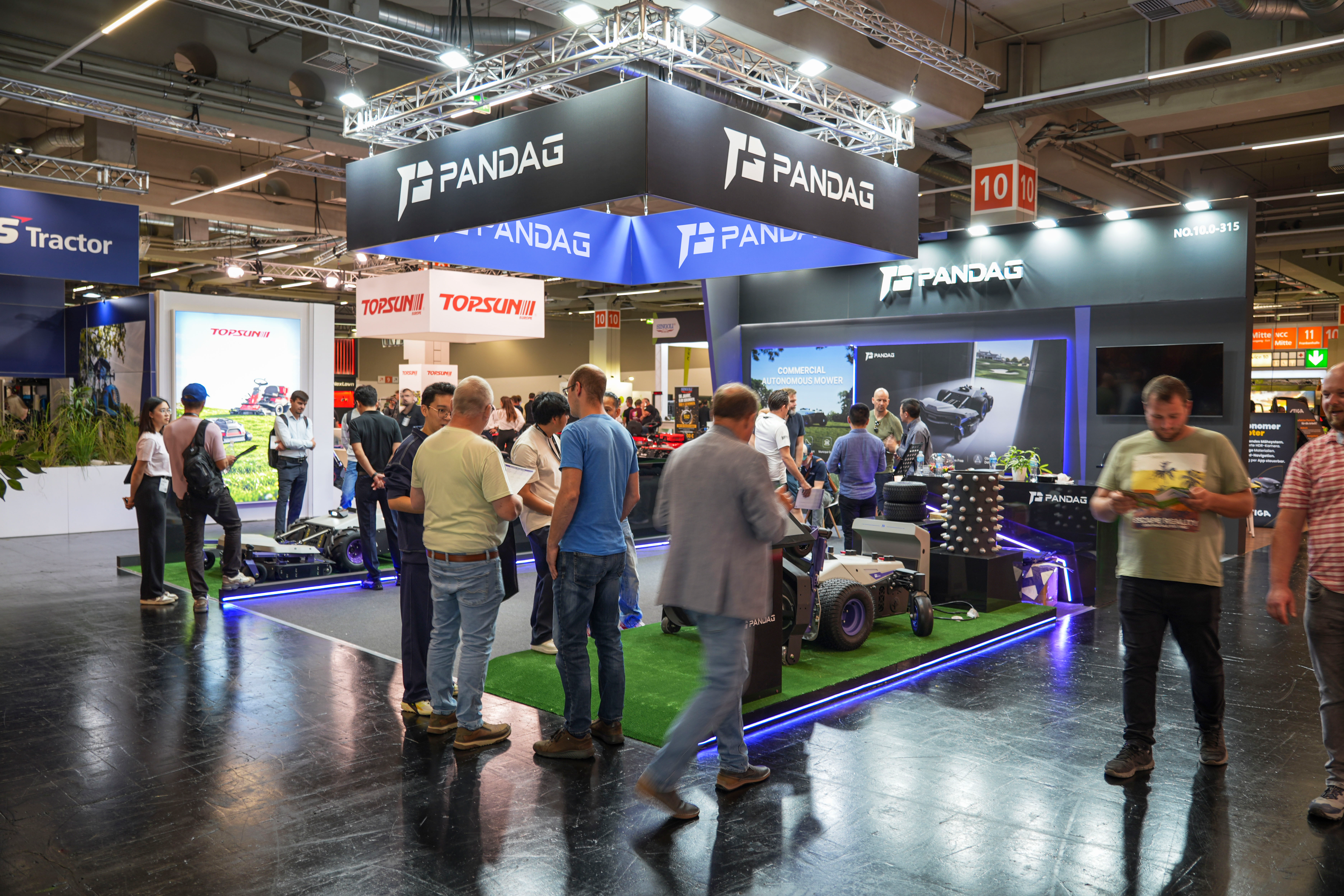 Visitors exploring the PANDAG G1 commercial robotic mower at the exhibition booth
