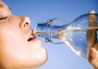 Woman drinking from a glass water bottle