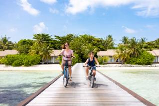 Mother and son riding bikes down a walk way in the Maldives