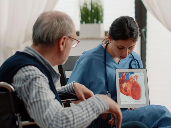 Infirmière tenant une tablette avec un cœur, diagnostic cardiologique