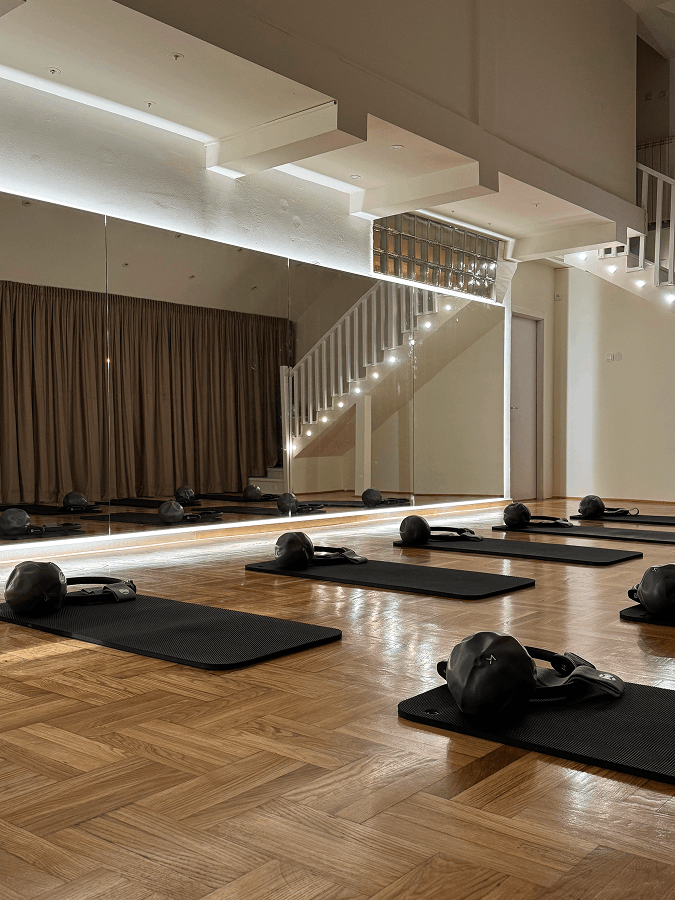 Seven Studio’s training room: exercise mats on a wooden floor beside a mirrored wall