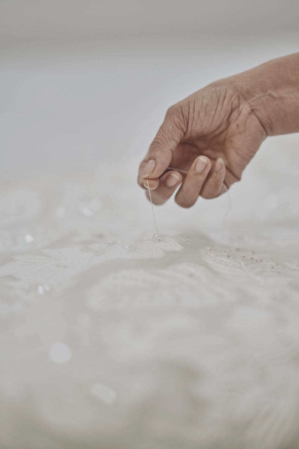 Hands attaching floral appliqué to a bridal gown