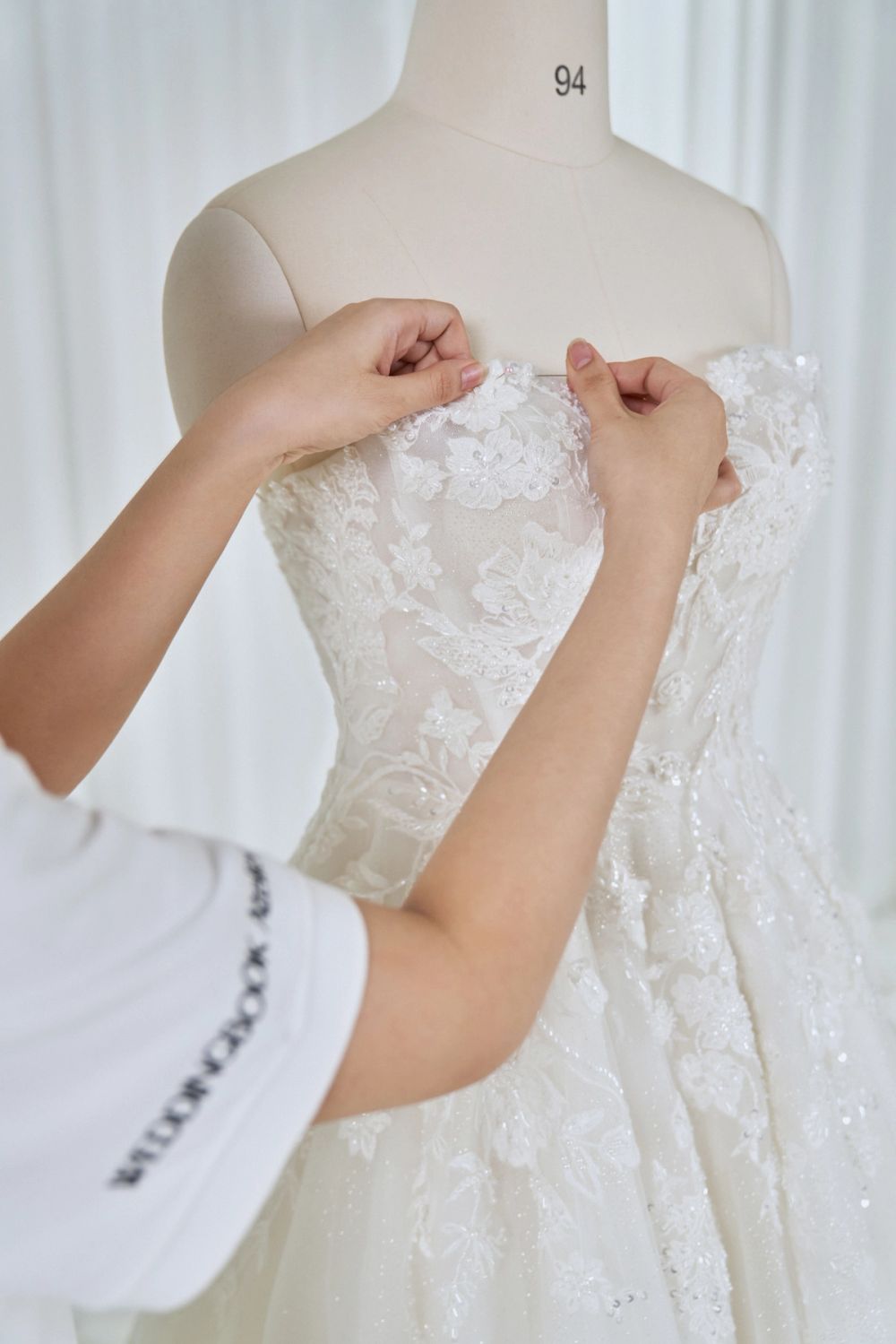 An atelier team member pinning a gown on a mannequin during a fitting
