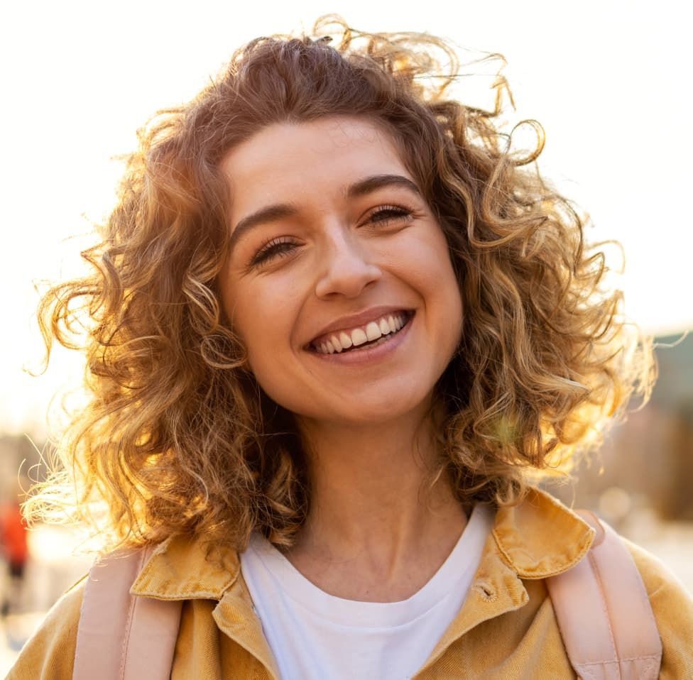lady with wavy hair smiling at the camera