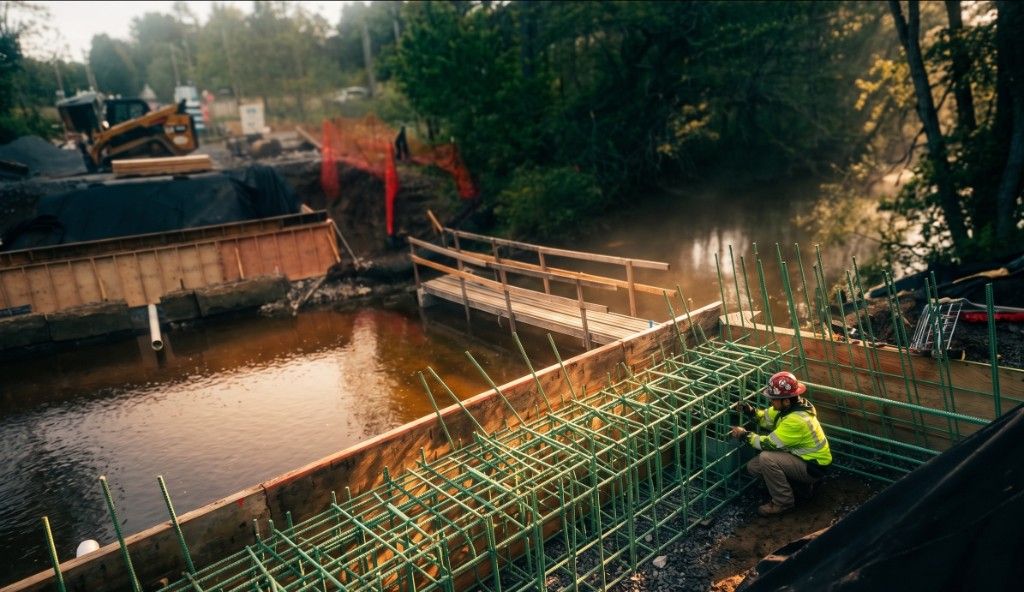 Construction worker in safety gear assembling rebar for a bridge foundation at a municipal jobsite.