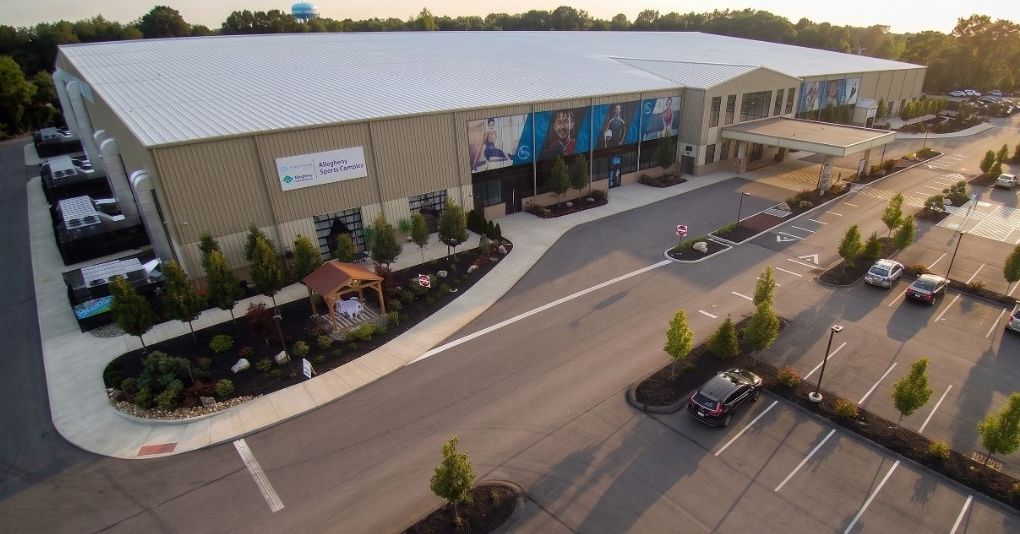 Aerial view of the Allegheny Sports Complex commercial building with parking lot and surrounding landscape.