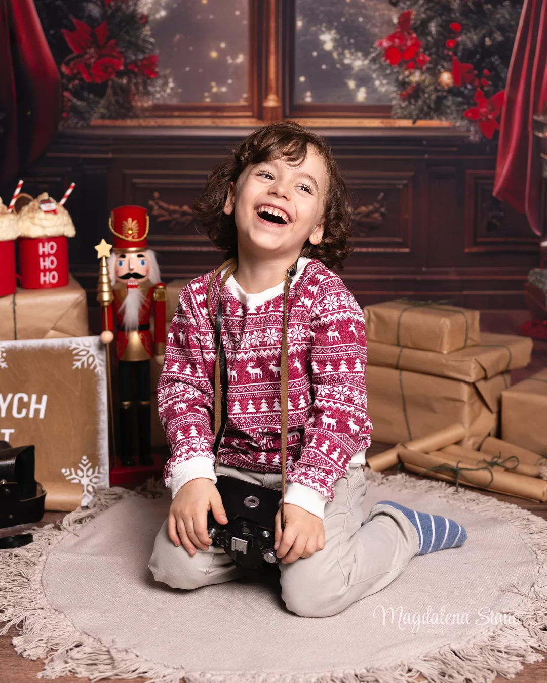 Fotograf przedszkolny Kraków, fotograf żłobek Kraków Fotograf w żłobku Kraków, uśmiechnięte dziecko otoczone prezentami na sesji świątecznej.