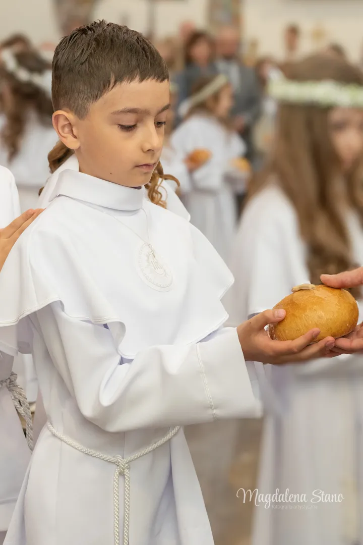 Fotograf na Komunię Świętą w Krakowie i okolicach: Reportaż z sesji klasowych i indywidualnych. fotograf-komunia-indywidualna-krakow-portret-dziecko-przyjmuje-chleb-od-ksiedza
