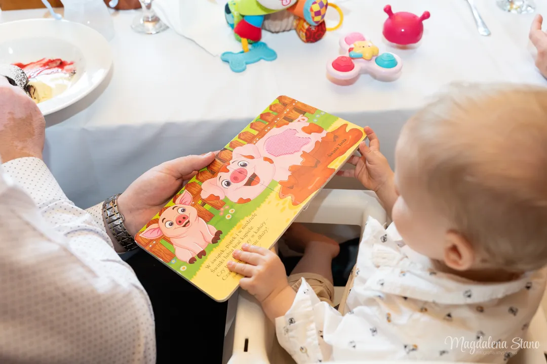 mama-pokazuje-ksiazke-dziecku-usmiechy-na-przyjeciu-chrzestnym