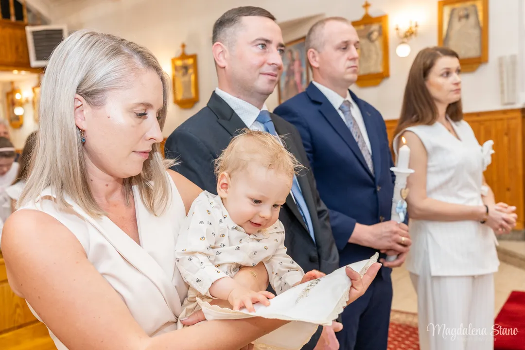 zdjecia-chrzest-rodzice-i-chrzestni-przed-oltarzem-dziecko-smieje-sie-do-szatki