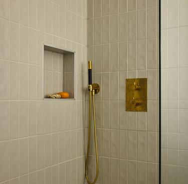 En moderne dusj i olivengrått med gulltetaljer.
