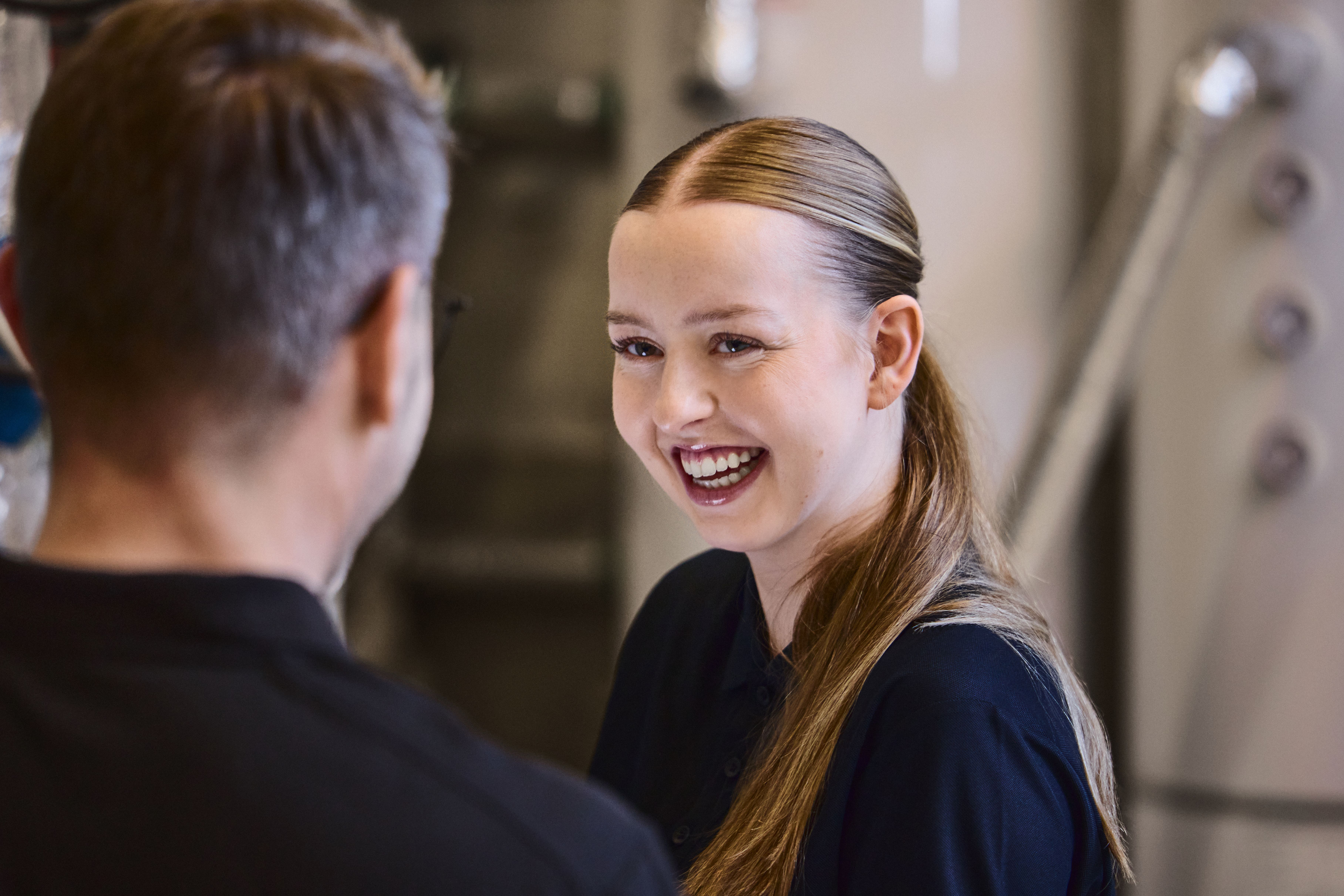 Smilende kvinne ser på mann som står med ryggen til kamera