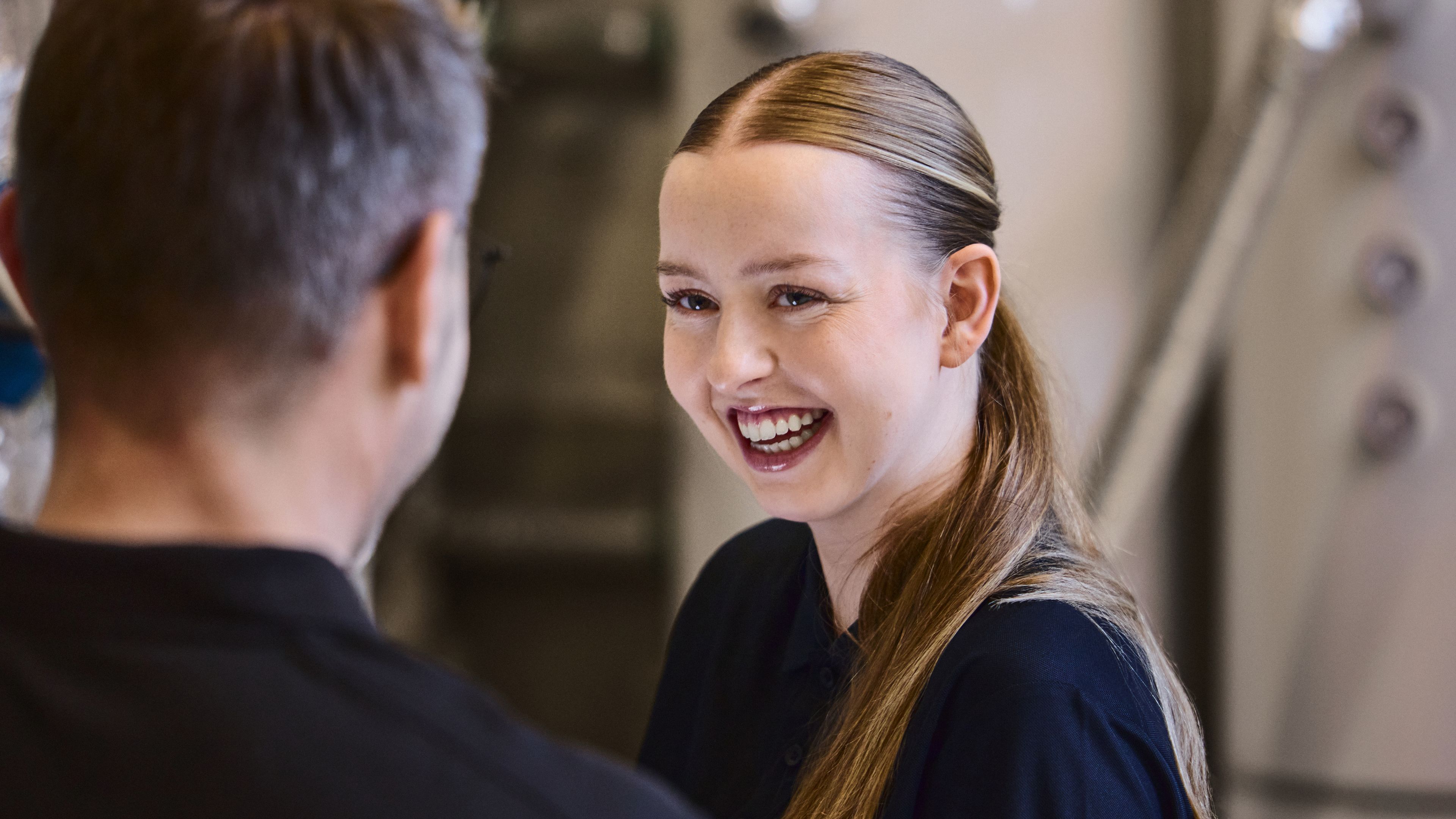 Smilende kvinne ser på mann som står med ryggen til kamera