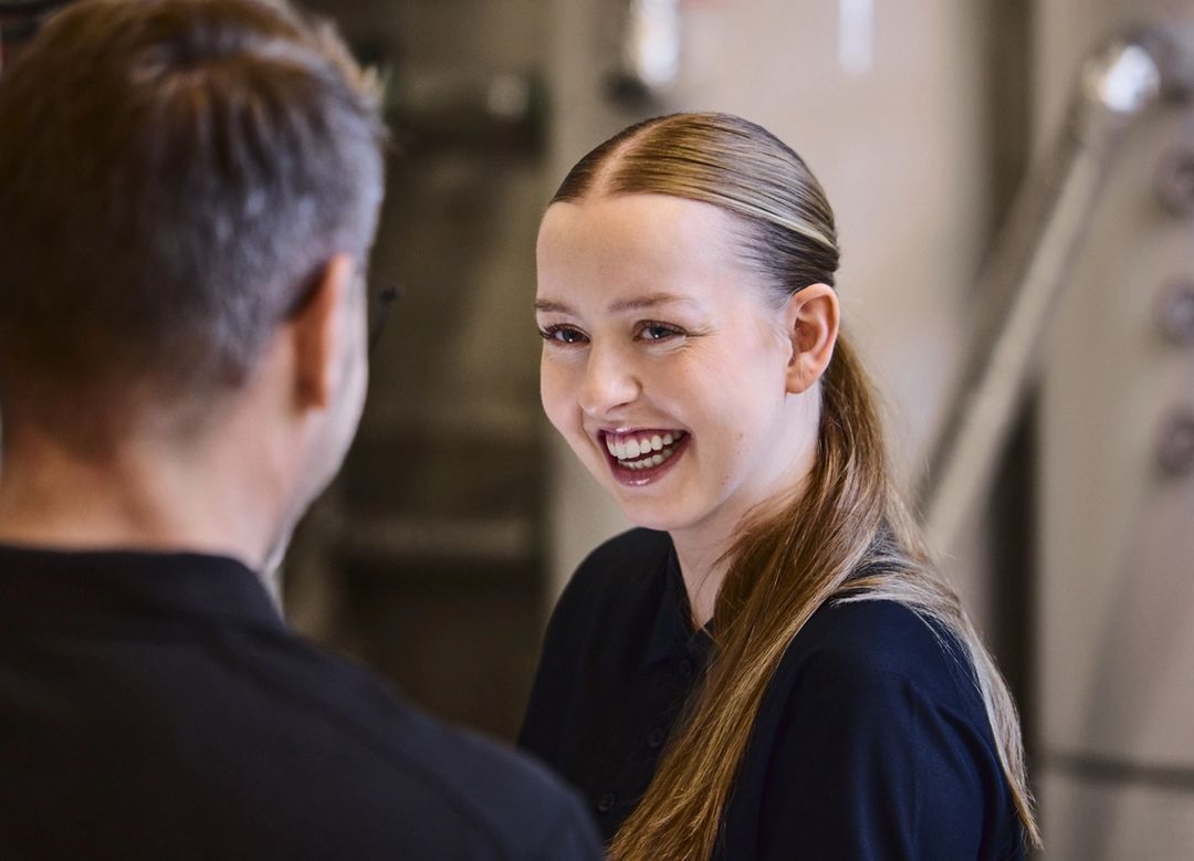 Smilende kvinne ser på mann som står med ryggen til kamera