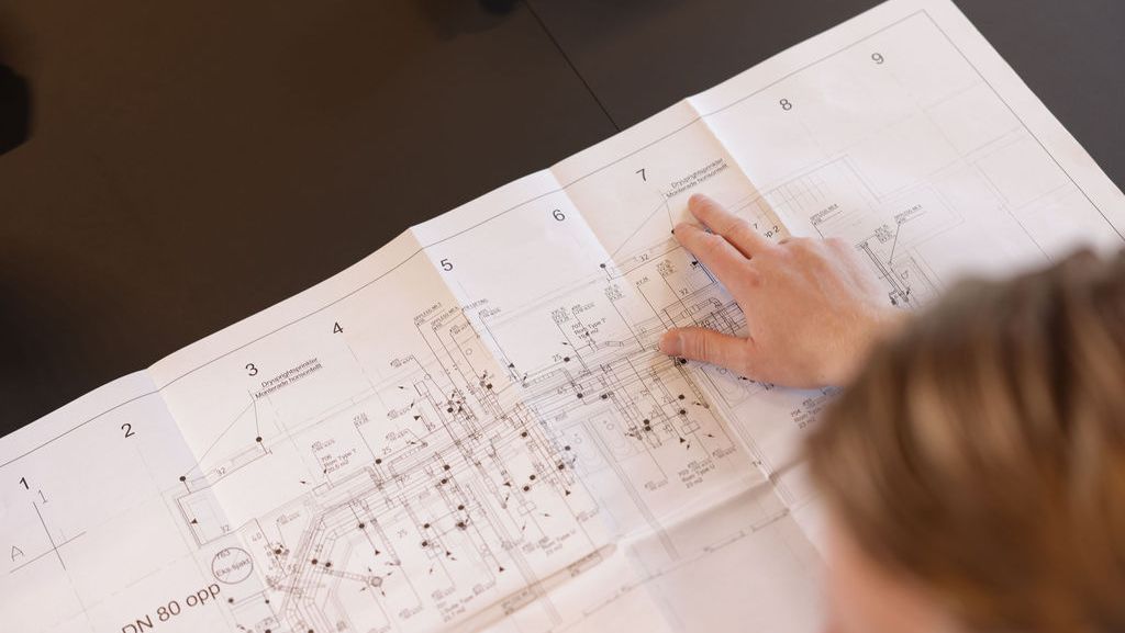 Hånd peker på punkt i plantegning