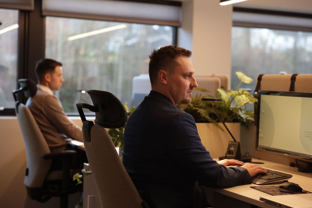 To menn ser inn i dataskjermen og trykker på tastaturet til pcen