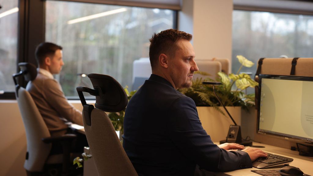 To menn ser inn i dataskjermen og trykker på tastaturet til pcen