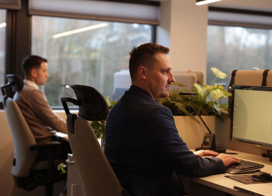 To menn ser inn i dataskjermen og trykker på tastaturet til pcen