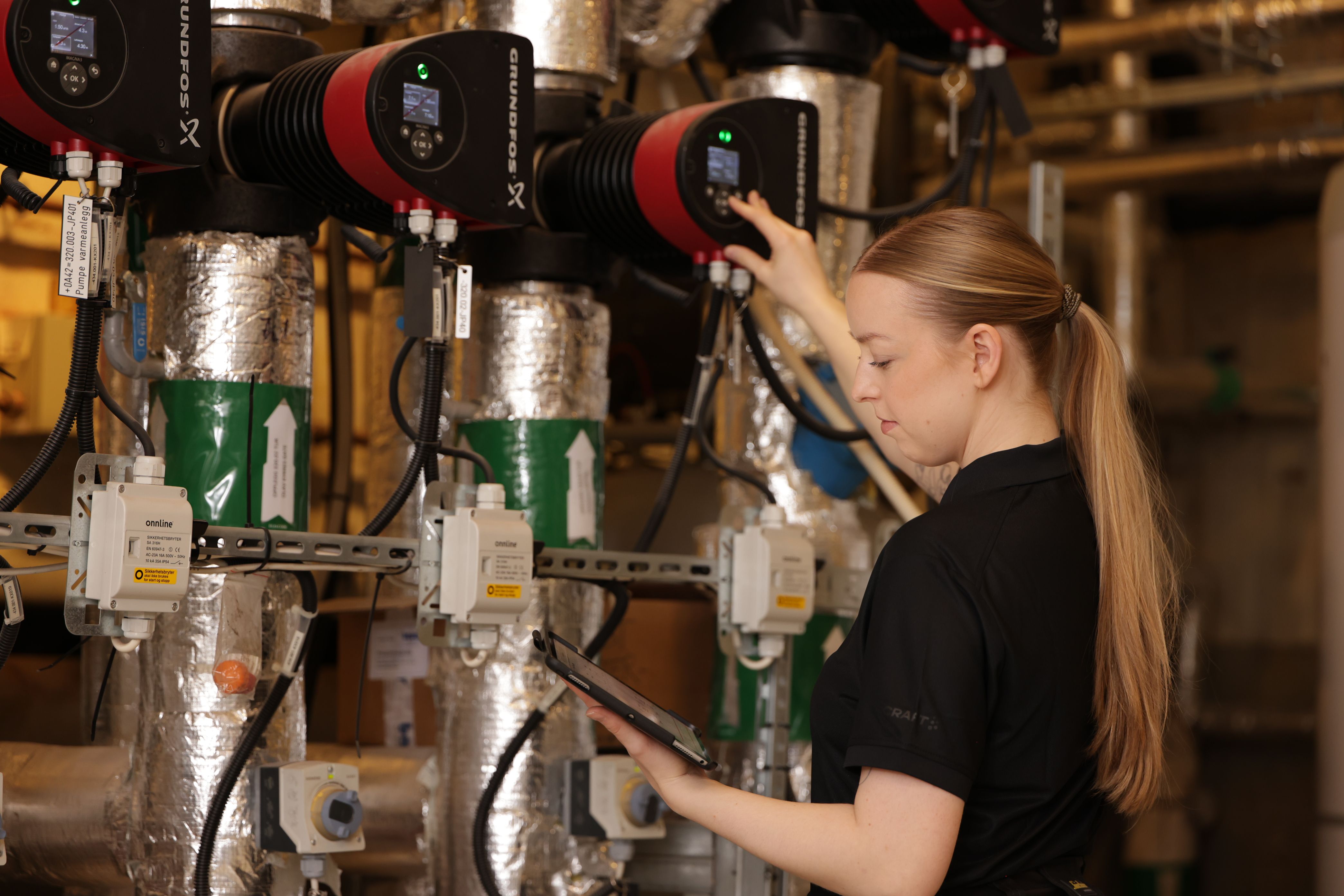 Kvinne ser på nettbrett og justerer på et panel 