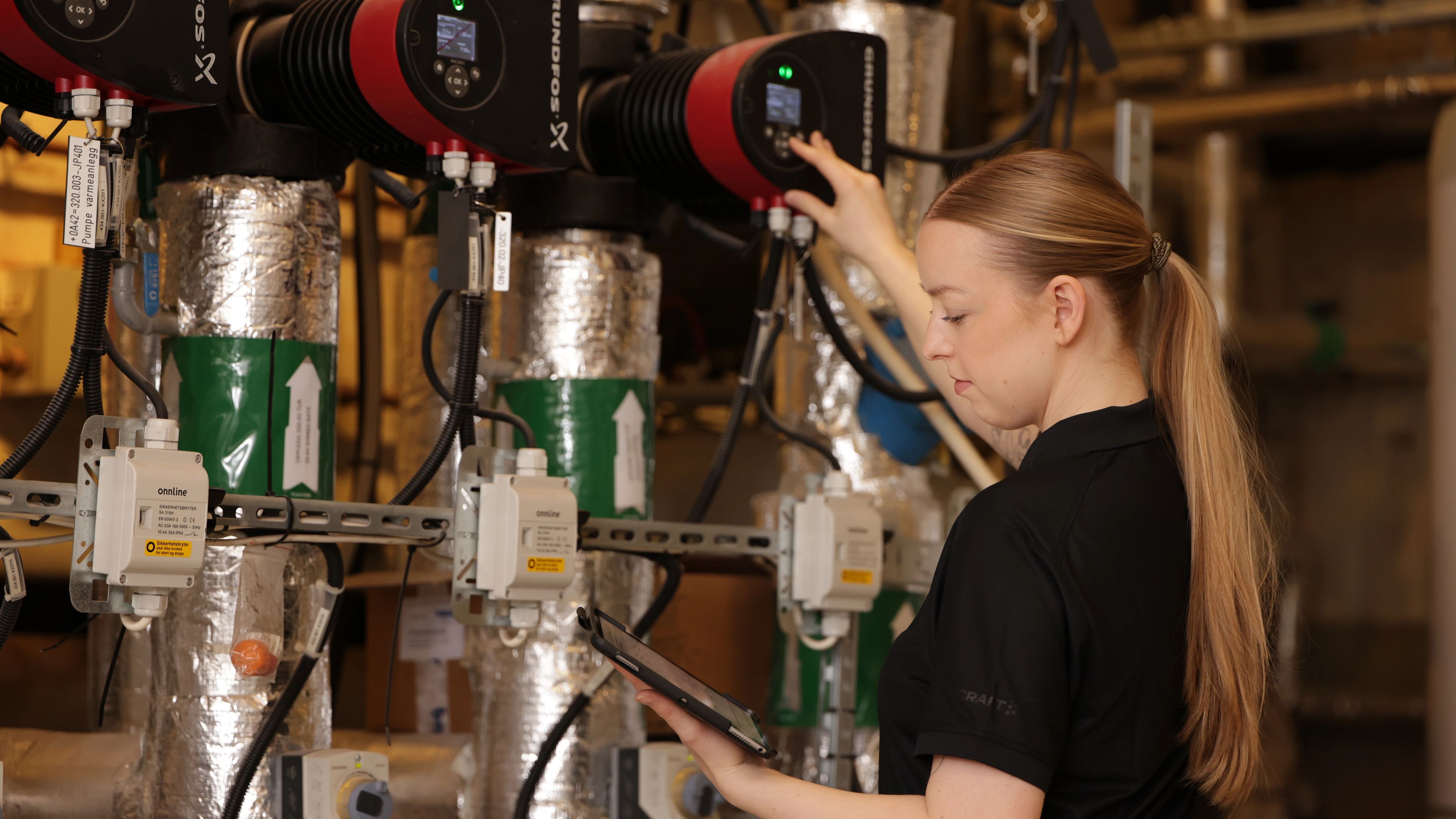 Kvinne ser på nettbrett og justerer på et panel