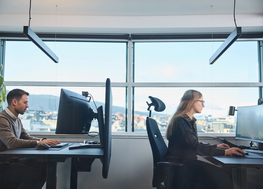 A man and a woman sitting at their desk and looking at their pc screens