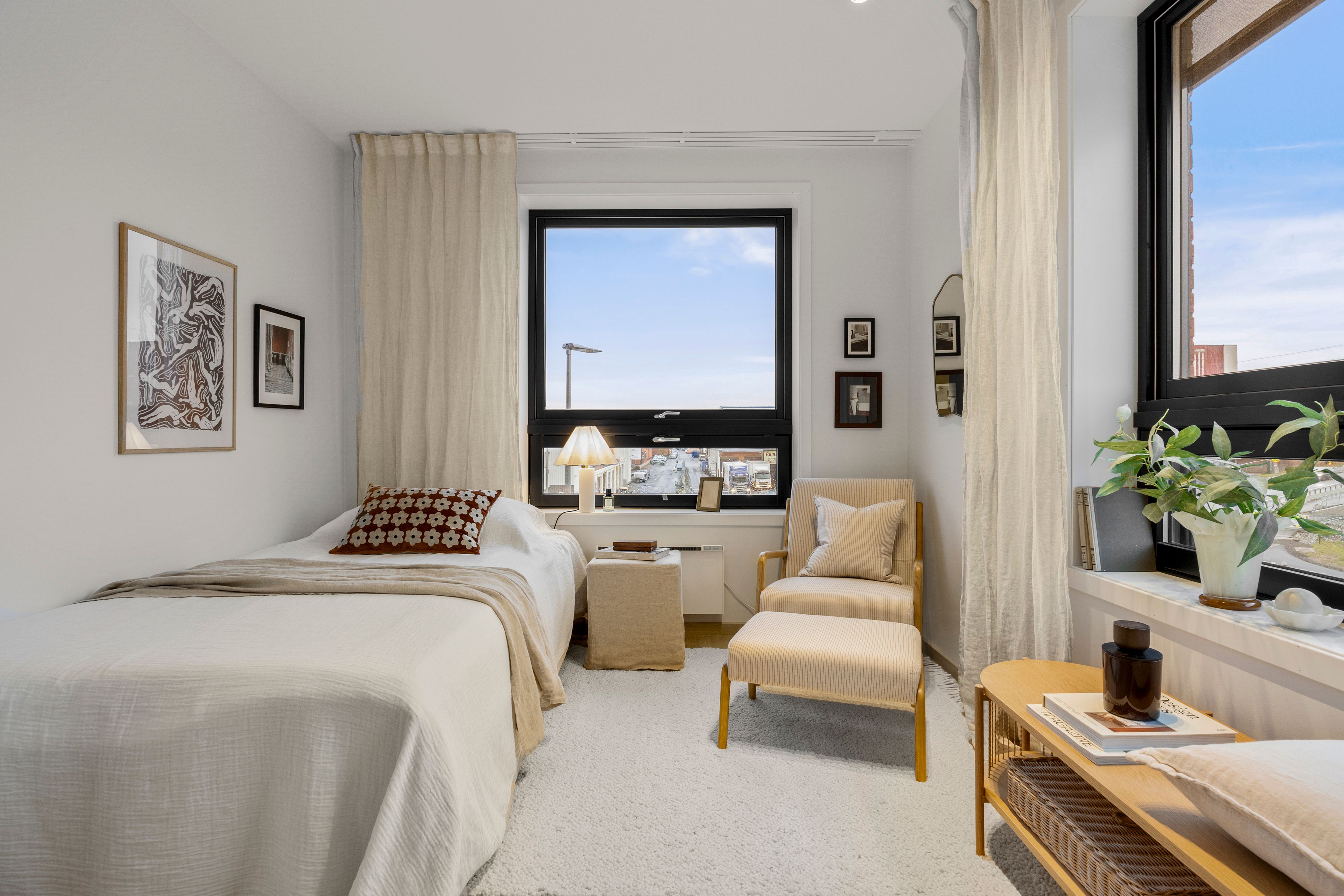 Soverom med seng og stol og oppbevaringsbenk.