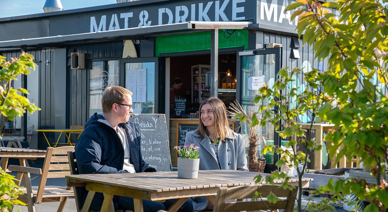 Et par som sitter på uteservering ved en kafé