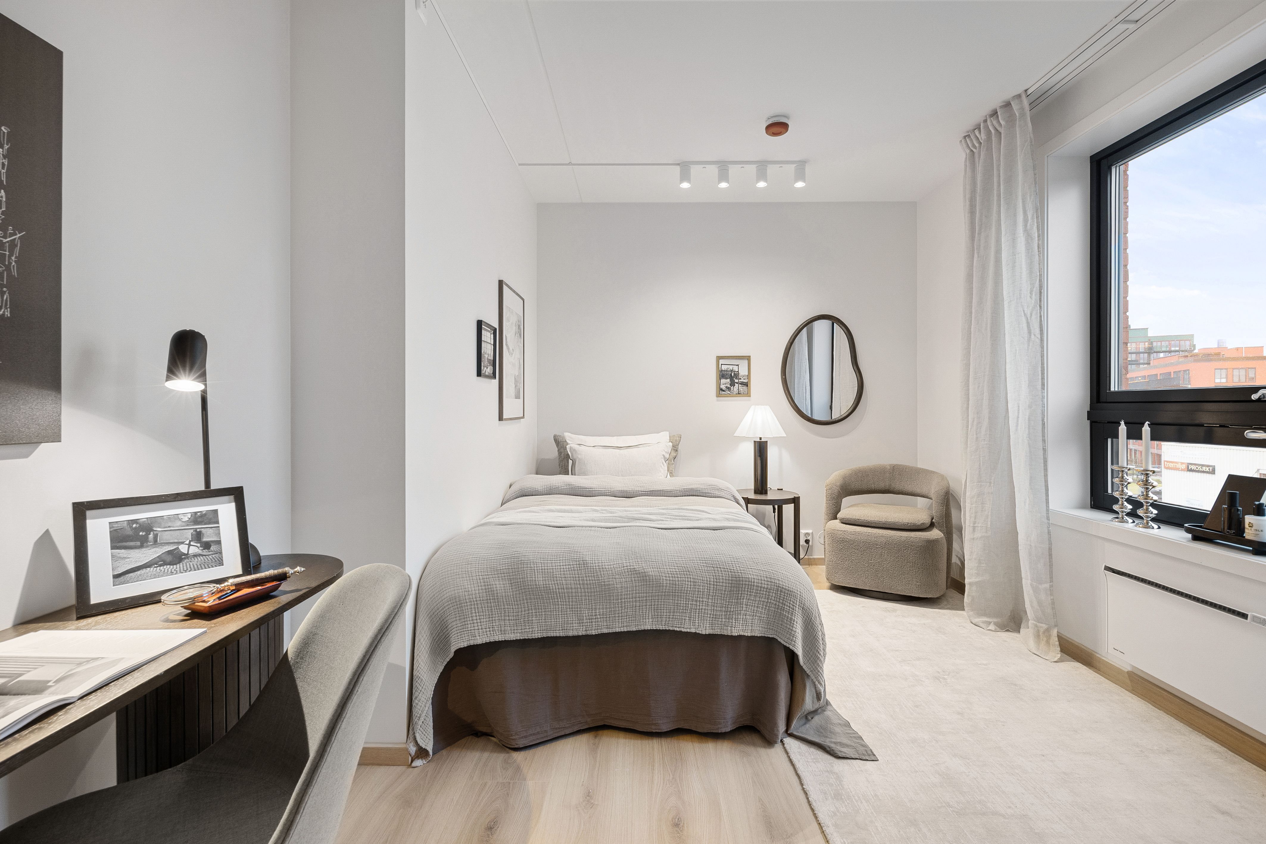 Soverom med seng, stol og skrivepult. Vindu med utsikt.