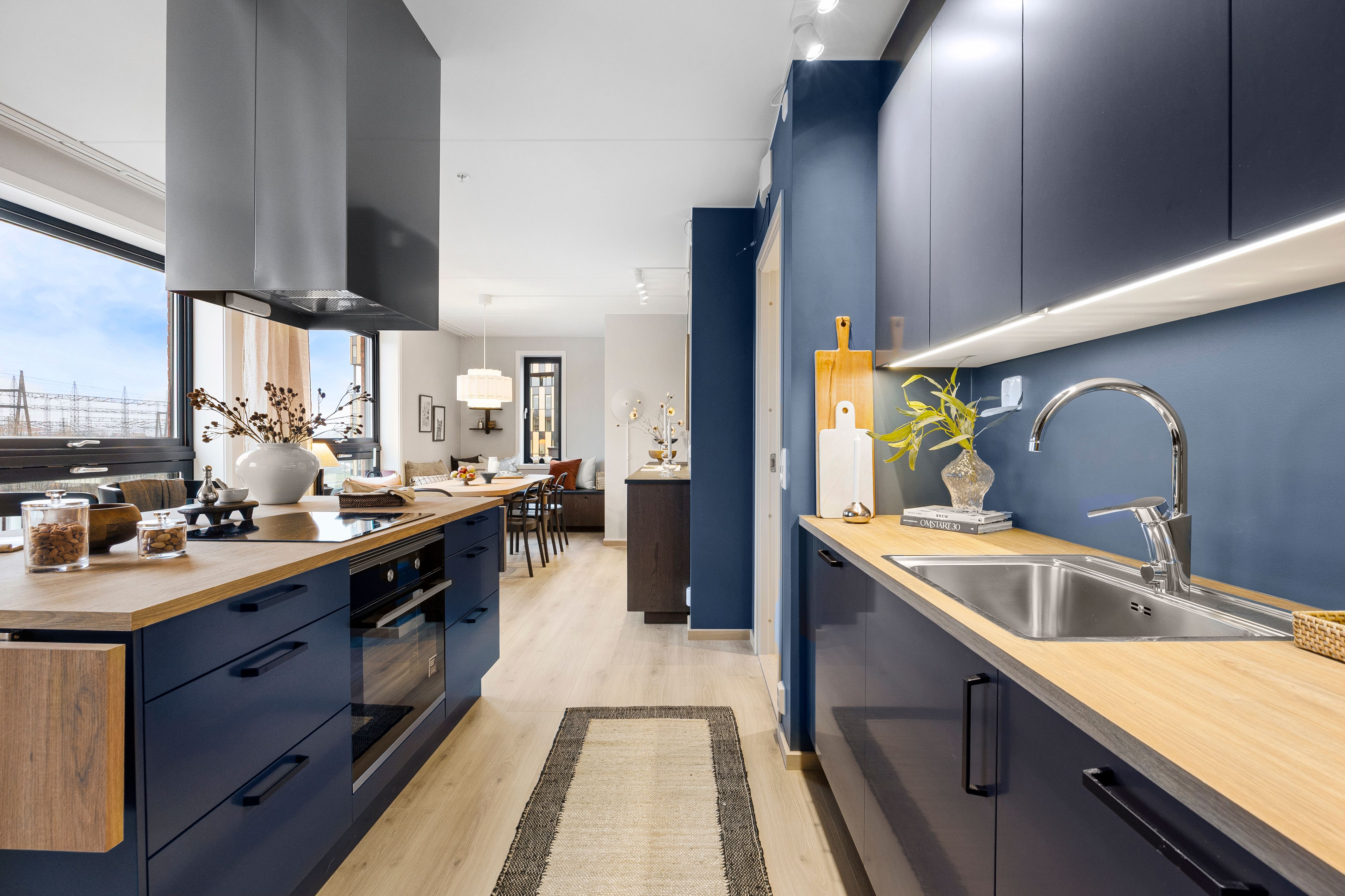 Kjøkken med kjøkkenbenk og kjøkkenøy. Spisebord i bakgrunnen