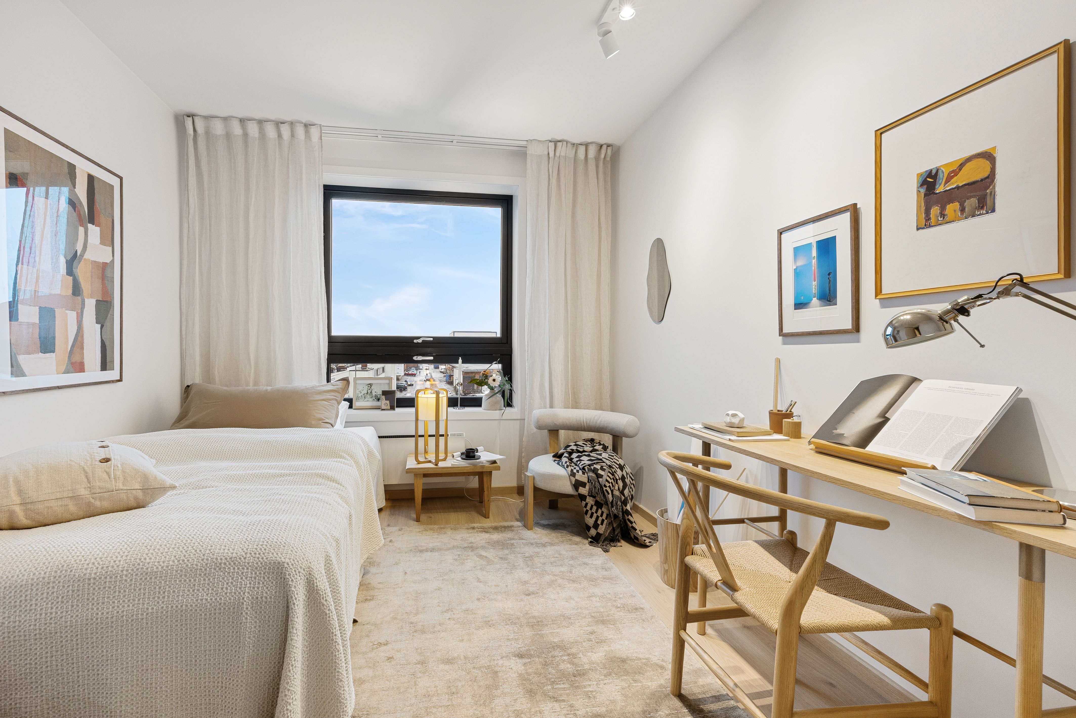 soverom med seng, stol, skrivepult og ett vindu.